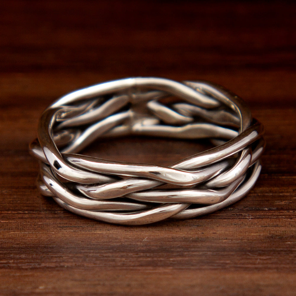 A silver ring featuring a tight weave design on a wooden background