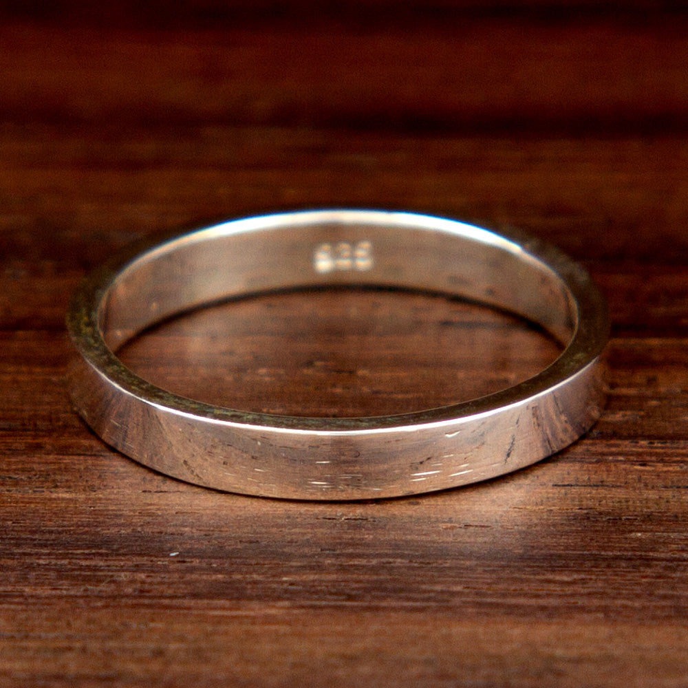 A classic silver mid-finger ring on a wooden background