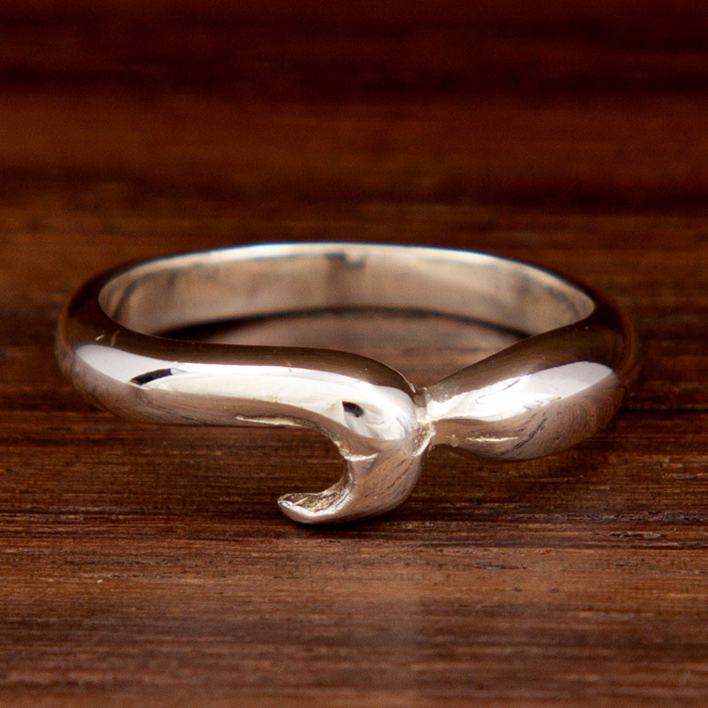 A silver mid-finger ring on a wooden background