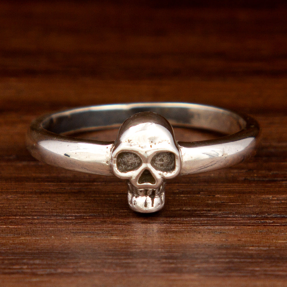 A silver ring featuring a skull on a wooden background