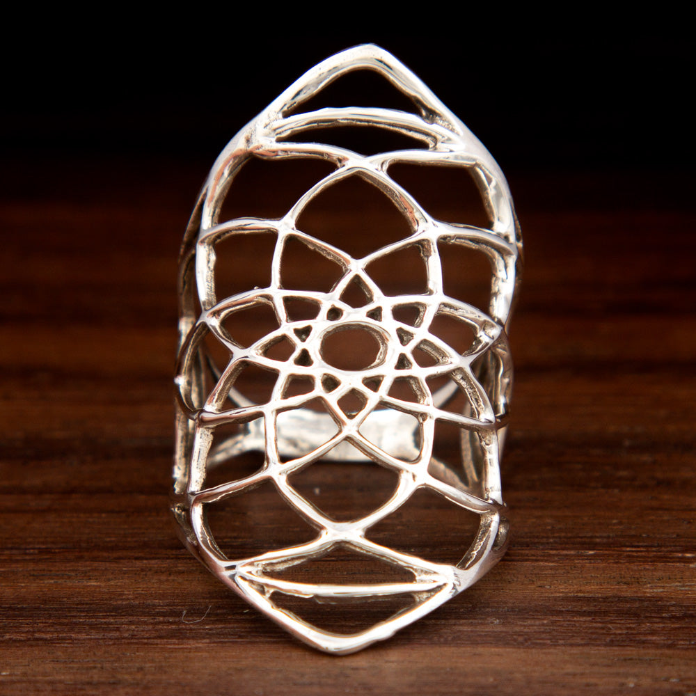 Long silver ring featuring a sacred geometry design on a wooden background