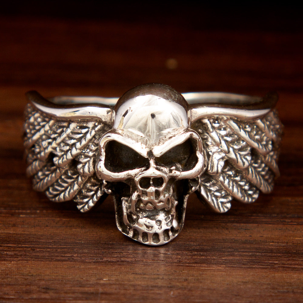 A thick silver ring featuring a skull design with wings on the sides