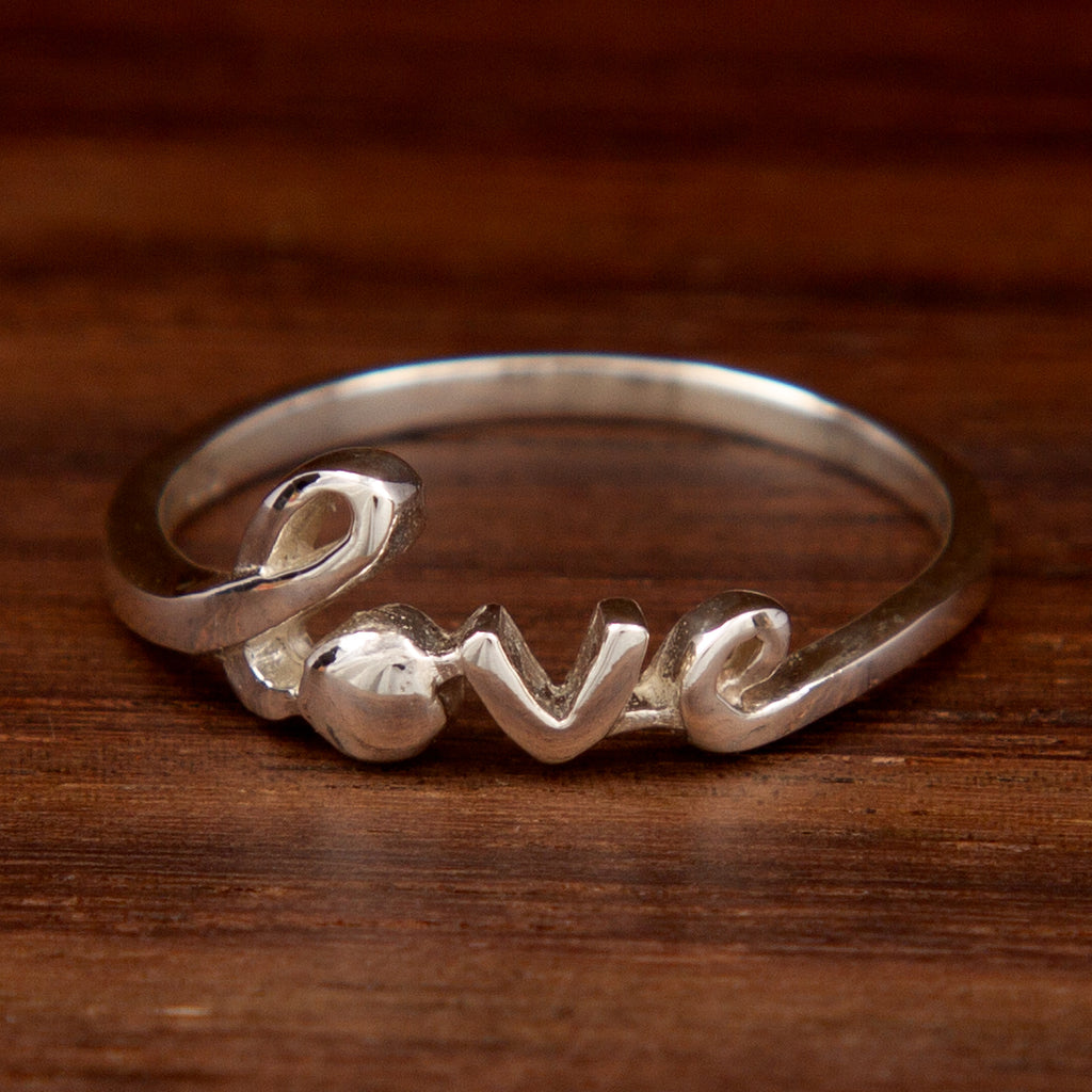 A sterling silver ring showcasing the word "Love" on a wooden background