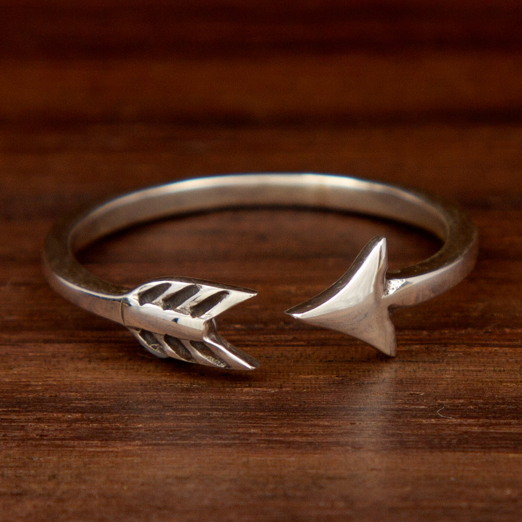 A sterling silver ring featuring an arrow design on a wooden background