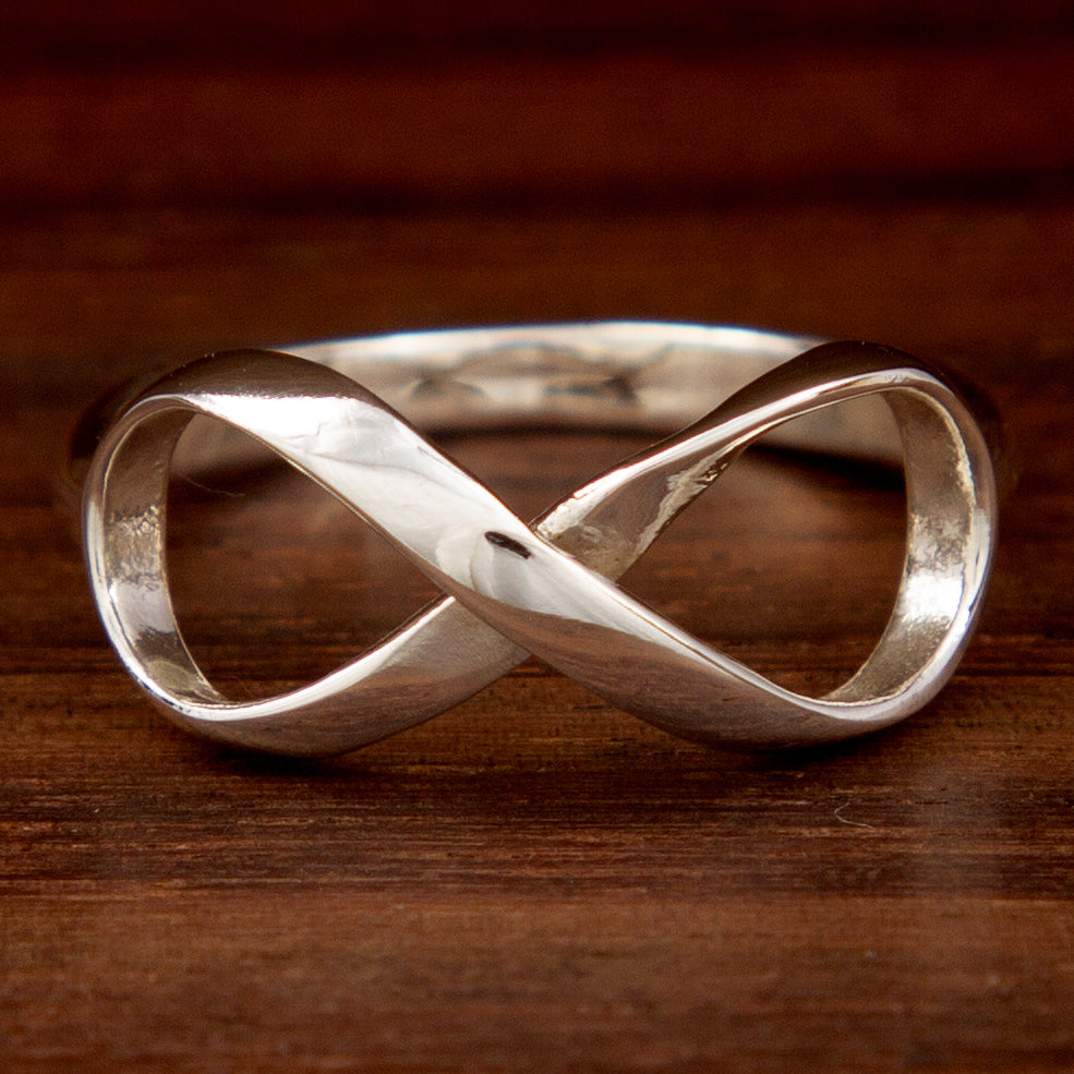 A silver ring featuring the infinity symbol on a wooden background