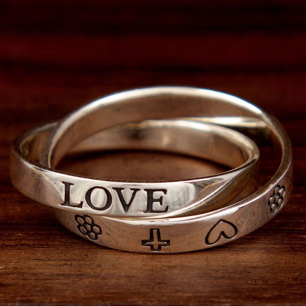 Two intertwined sterling silver rings featuring words and symbols of love, faith, hope