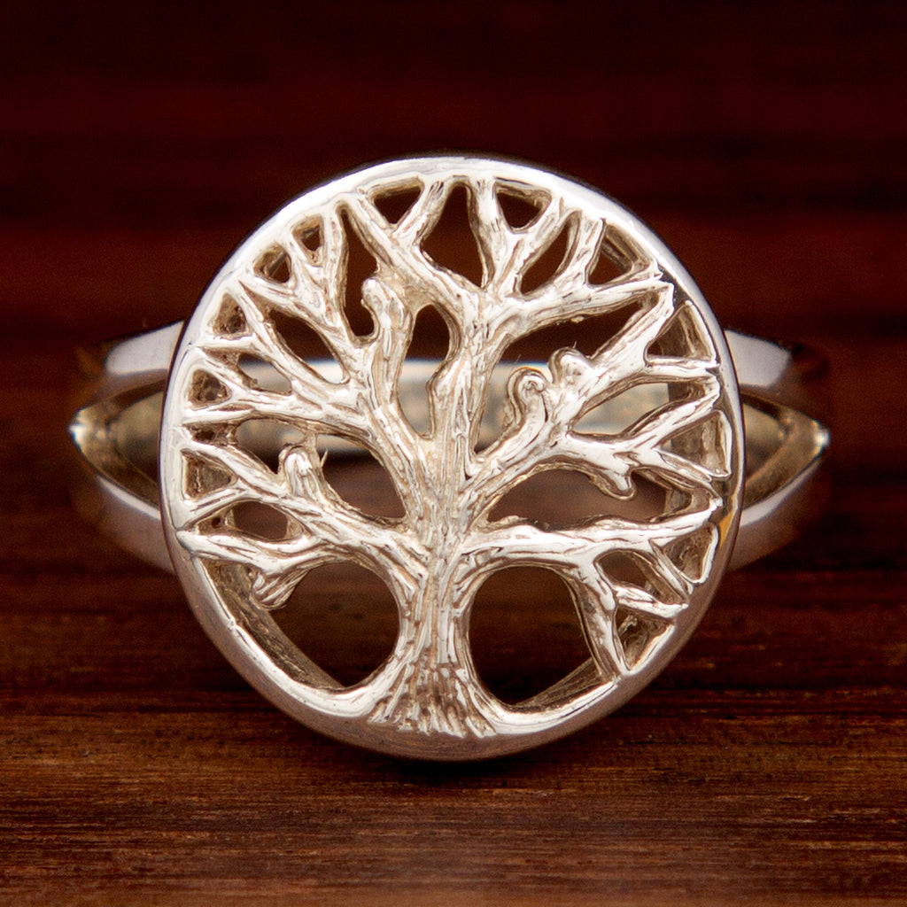 A sterling silver ring featuring a tree of life design on a wooden background