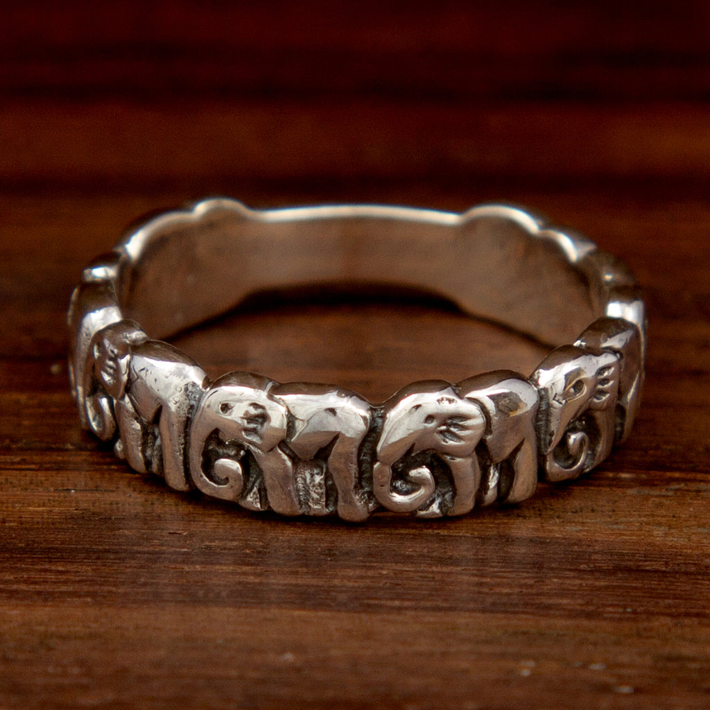 A silver ring featuring an elephant band design on a wooden background