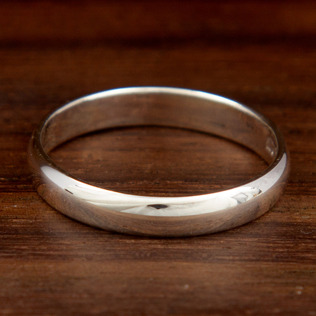 A classic silver band ring on a wooden background