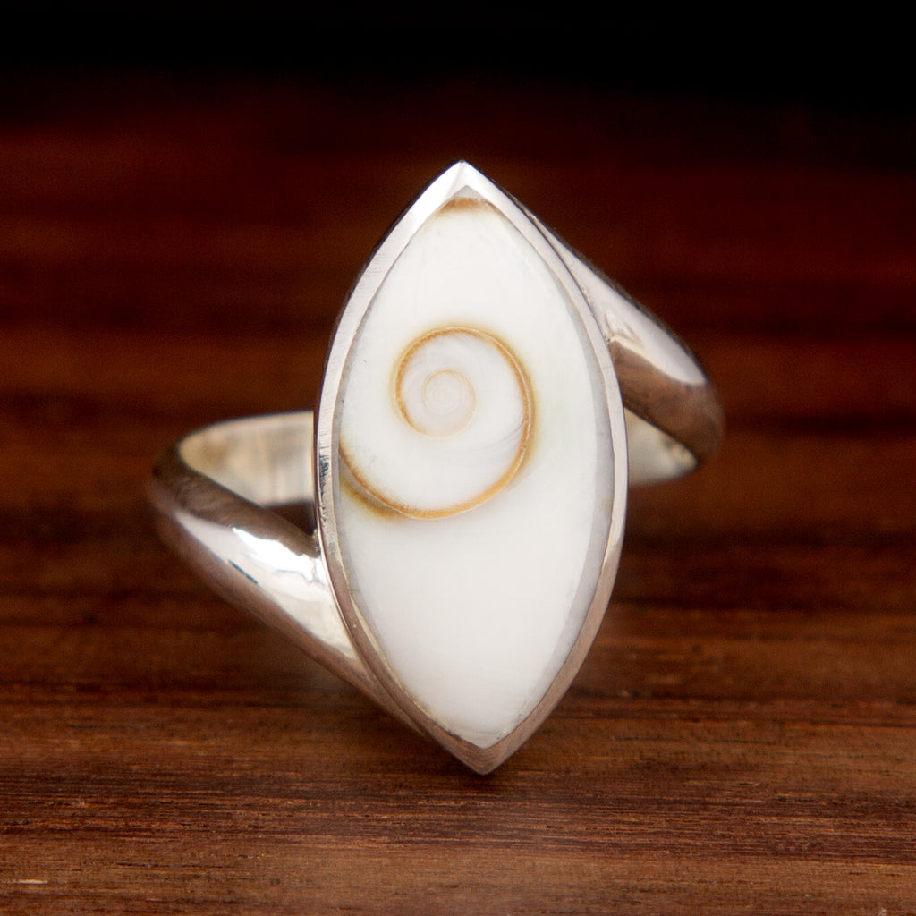 Silver ring featuring a shell design featuring an "eye" shape on a wooden background