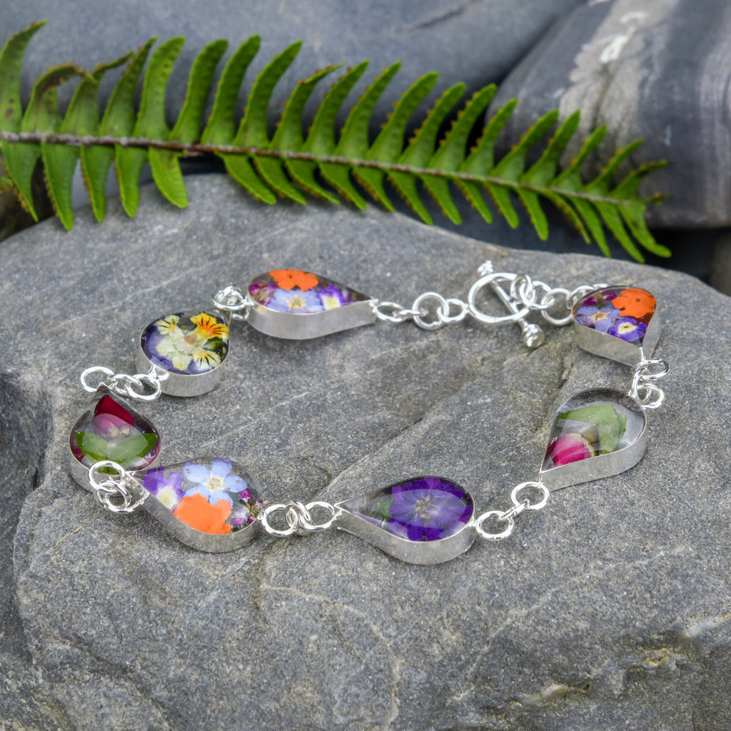 san marco silver and resin bracelet with various coloured dried flowers encased in the resin of seven small droplet shaped sections and joined by silver links