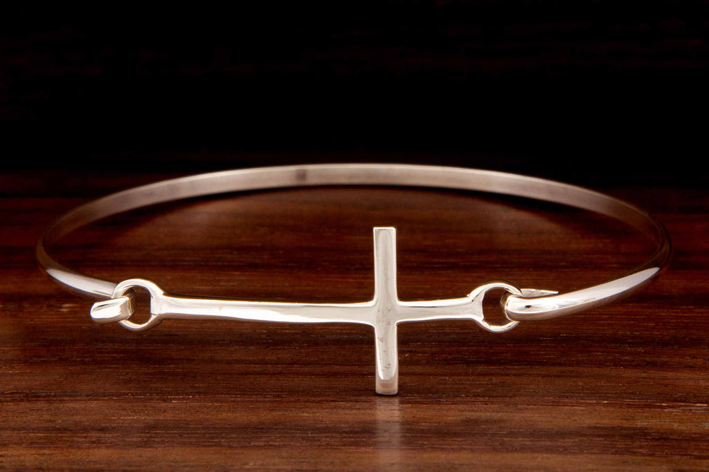 A silver bangle featuring a cross design on a wooden background
