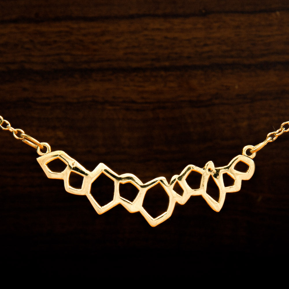 A brass pendant featuring a chain or irregular geometric forms