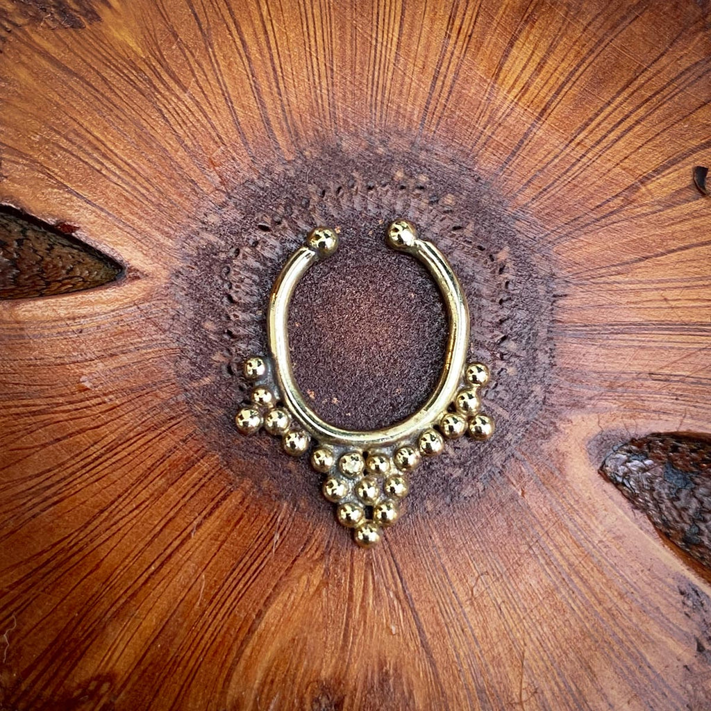 A brass press on septum jewel on a wooden background
