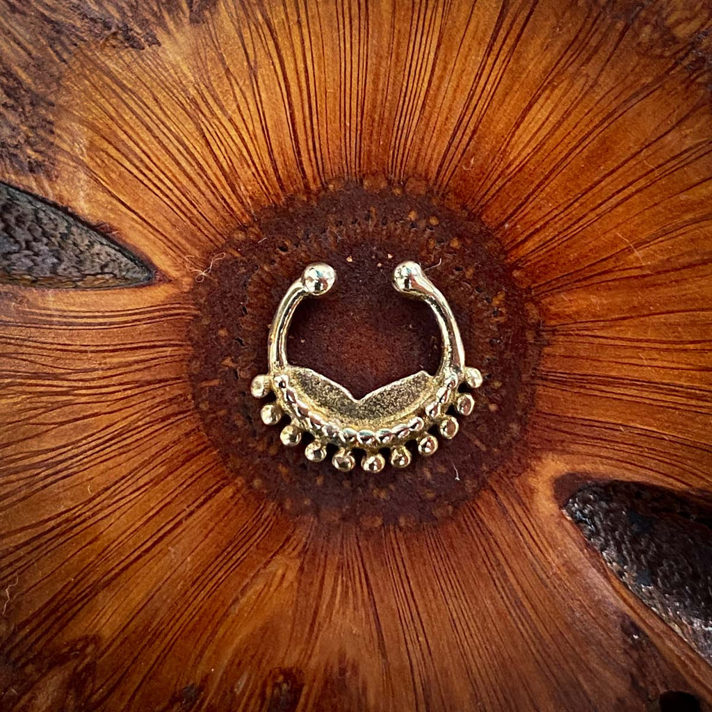A brass fake septum decorated with dots